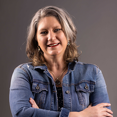 Portrait of Shelly Dretzka wearing a denim jacket with her arms crossed